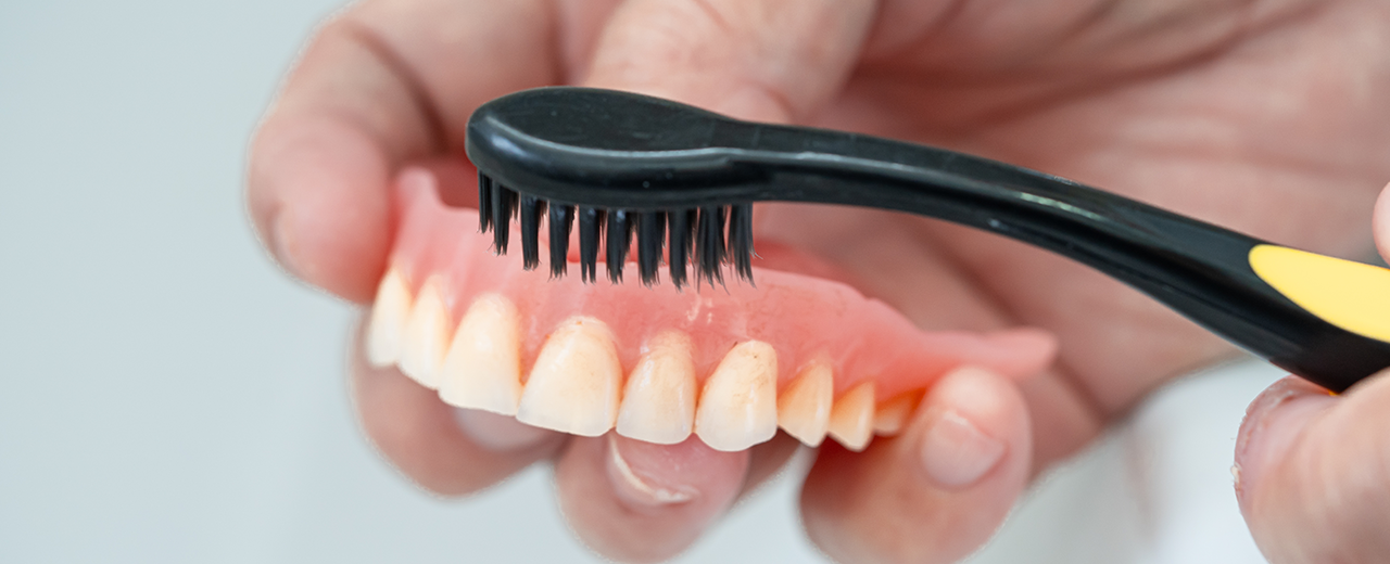 Patient cleaning the denture using a soft bristle brush. 
